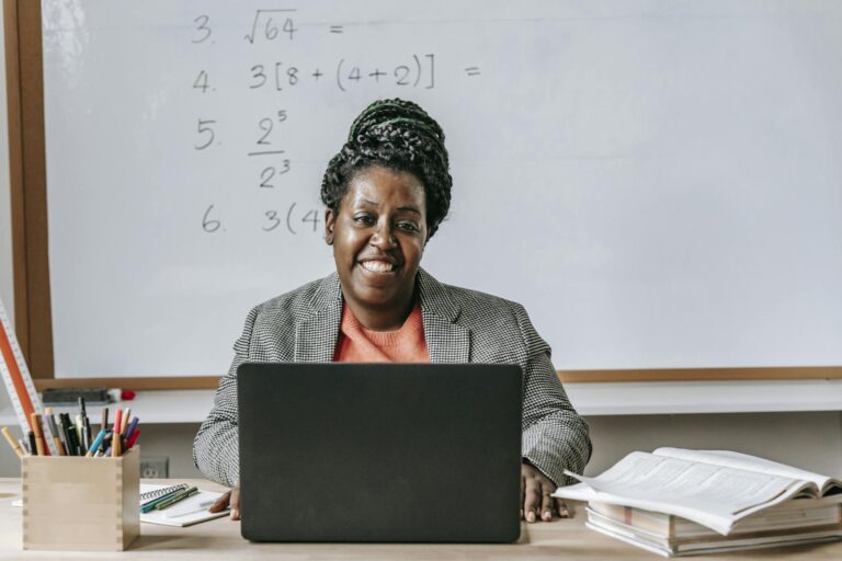 Positive black woman with laptop smiling in classroom